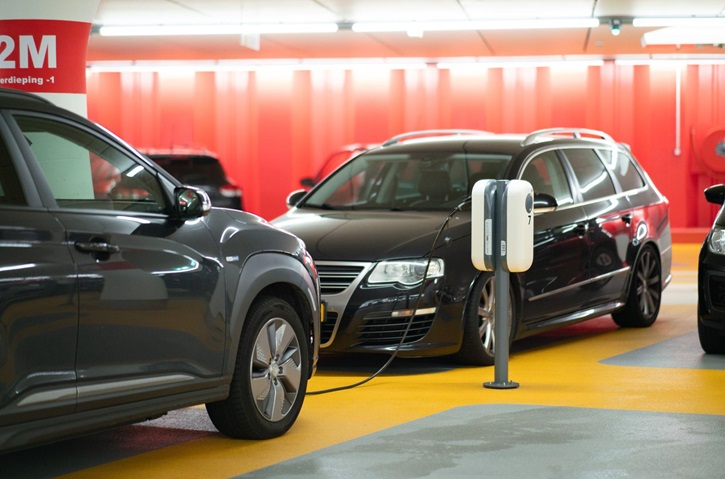 Electric cars at a charging station represent how the auto industry and CarGuard have evolved over time